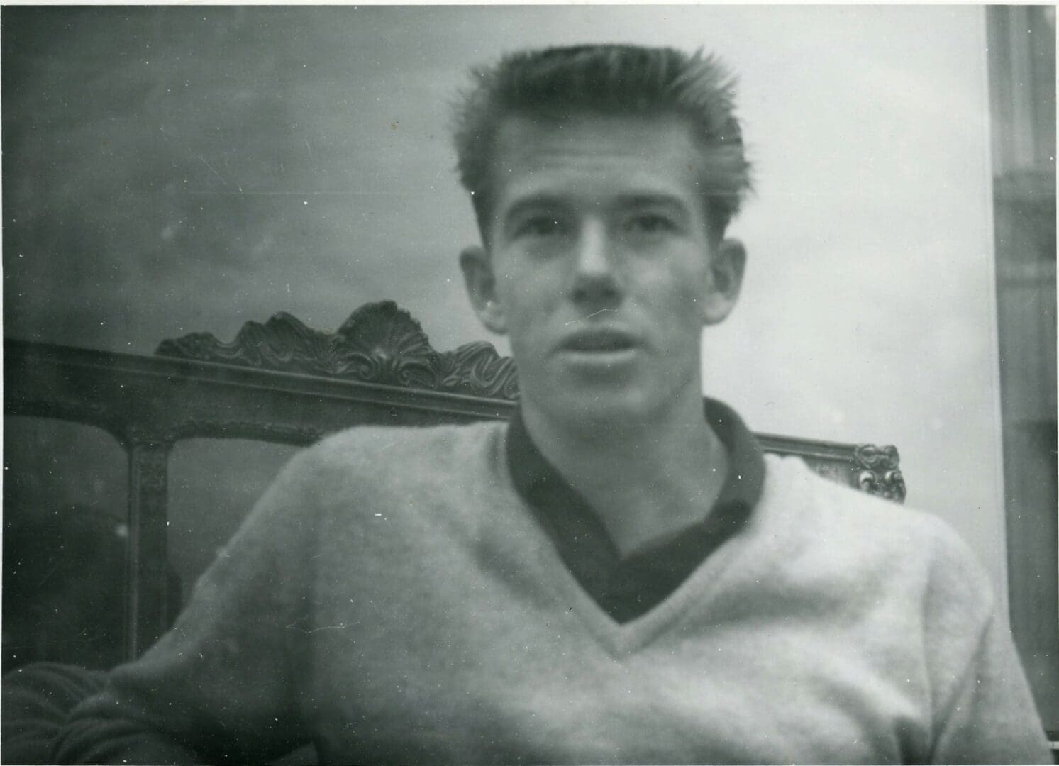 A young man in a sweater is posing for the camera.