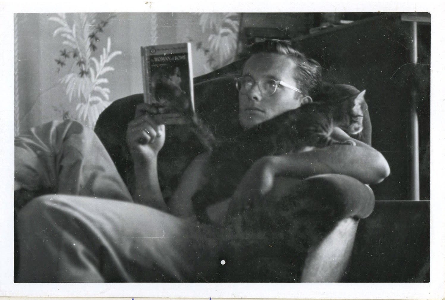 A man sitting on the couch reading a book.
