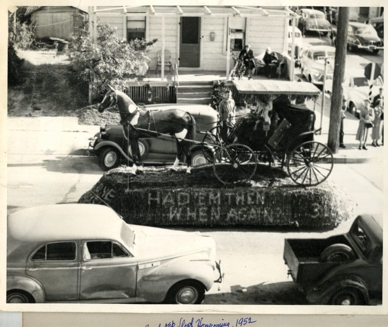 A black and white photo of cars parked on the side of a road.