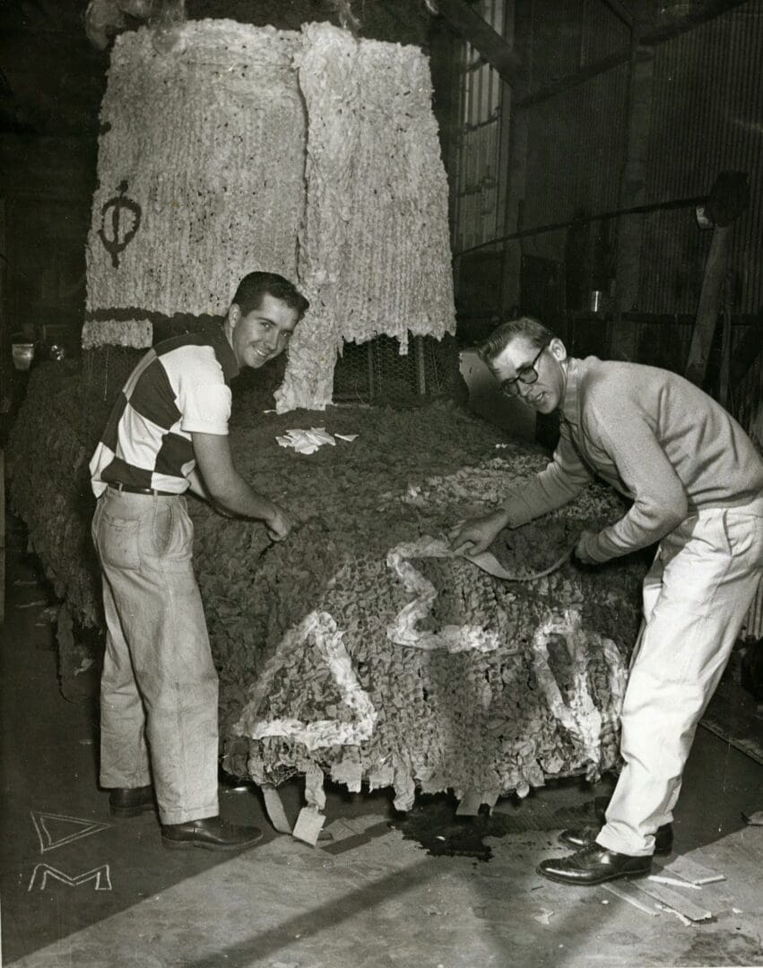 Two men are working on a bed in the middle of an old room.