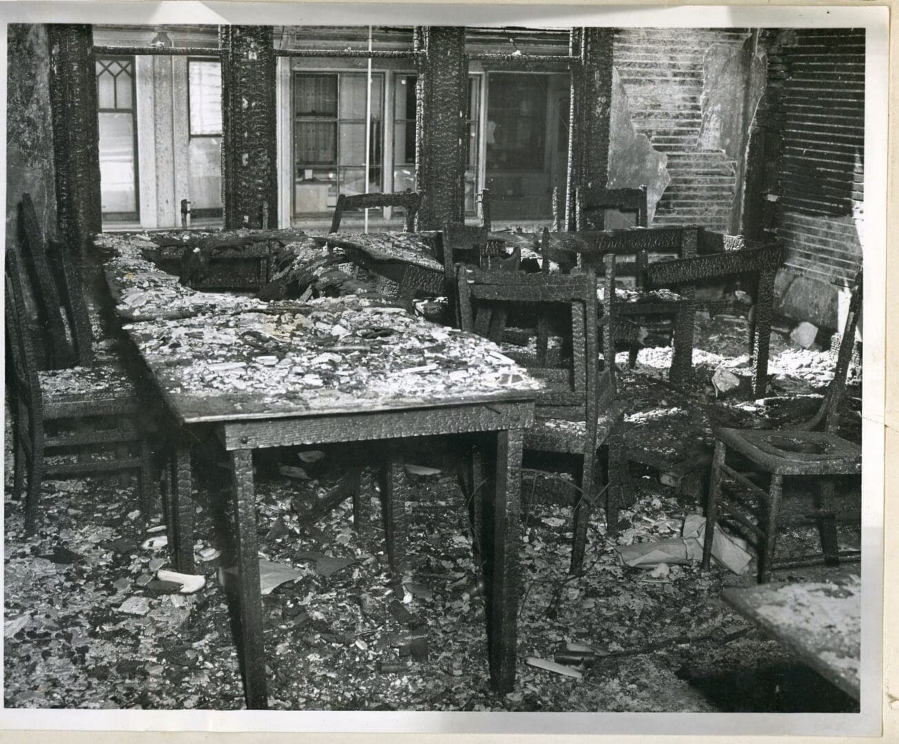 A room with many tables and chairs covered in debris.