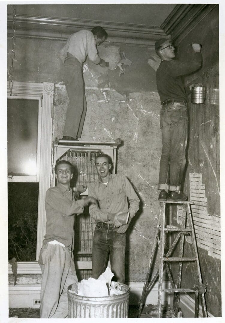 Two men standing in a room with some ladders.