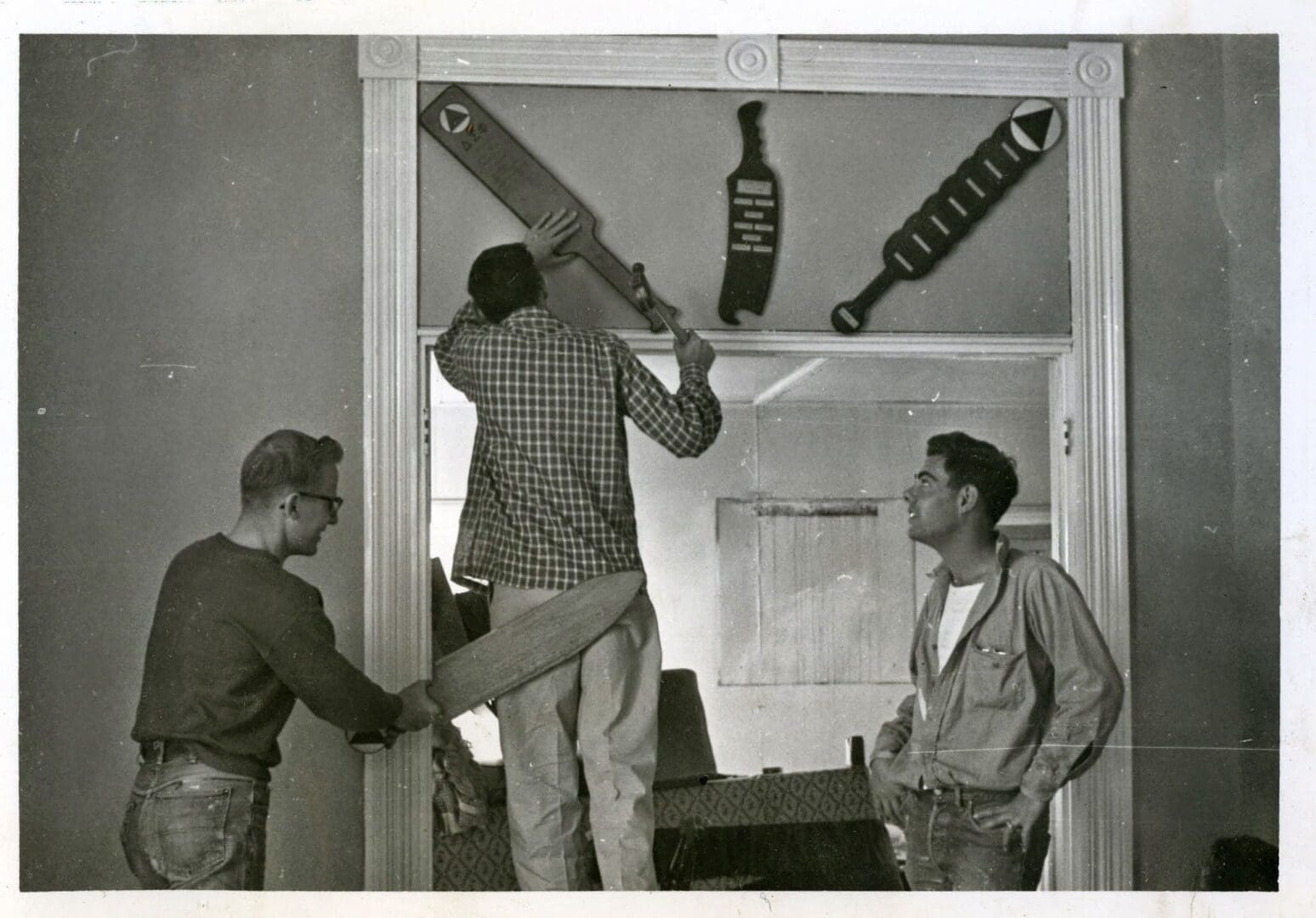 Three men are hanging up a beer bottle.