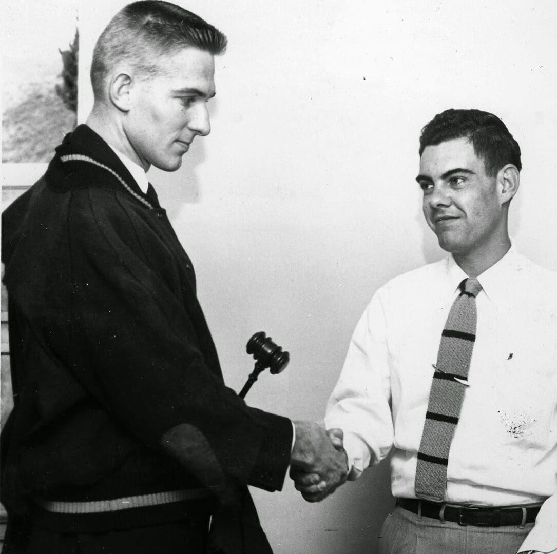 A man shaking hands with another man in front of a microphone.