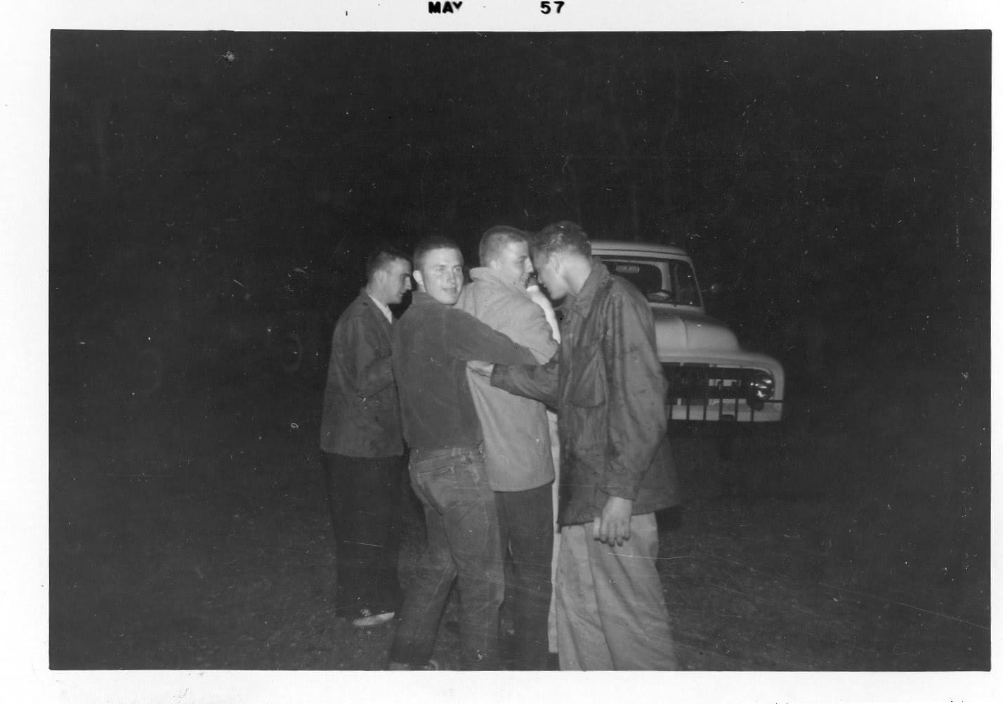 Three men standing in front of a truck.