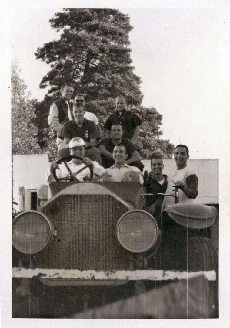 A group of people sitting on top of an old car.