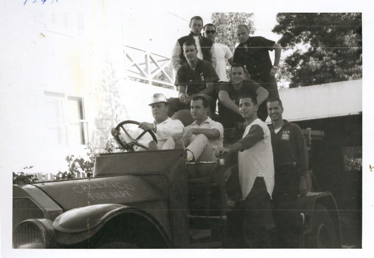A group of men standing around an old car.