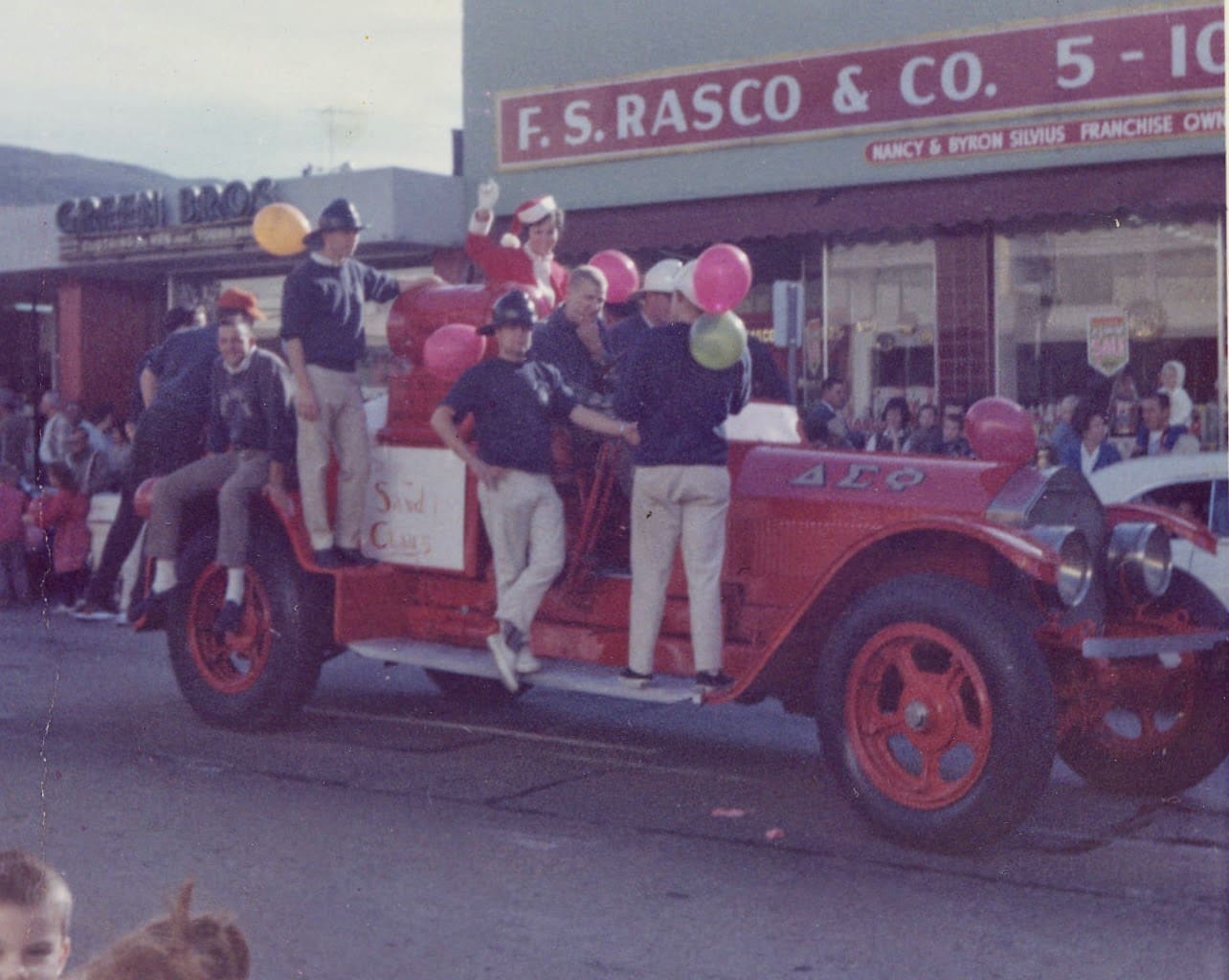 A group of people riding in the back of an old fire truck.
