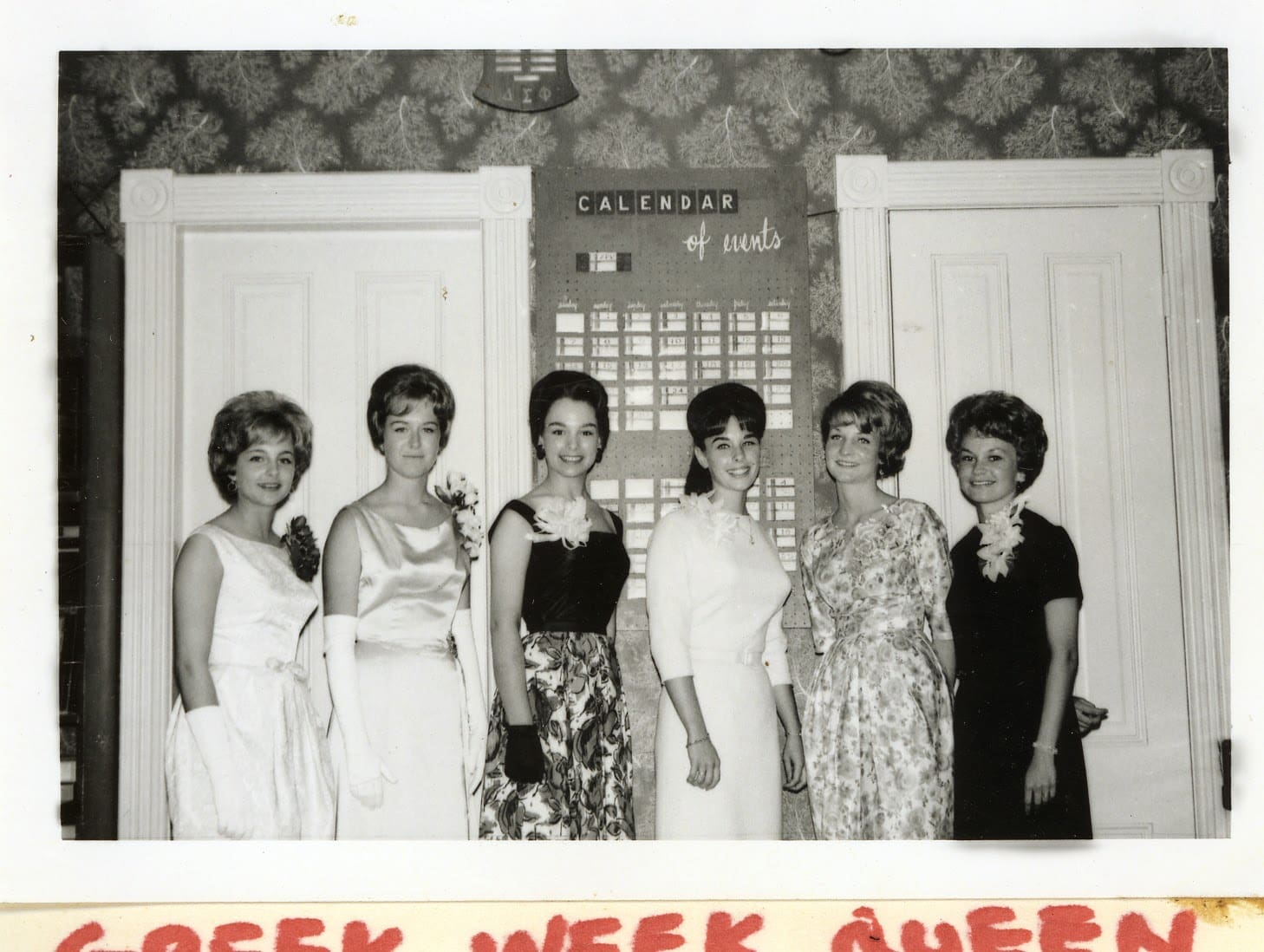 A group of women standing in front of a wall.