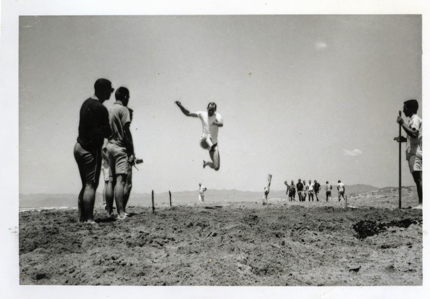 A man jumping in the air over some sand