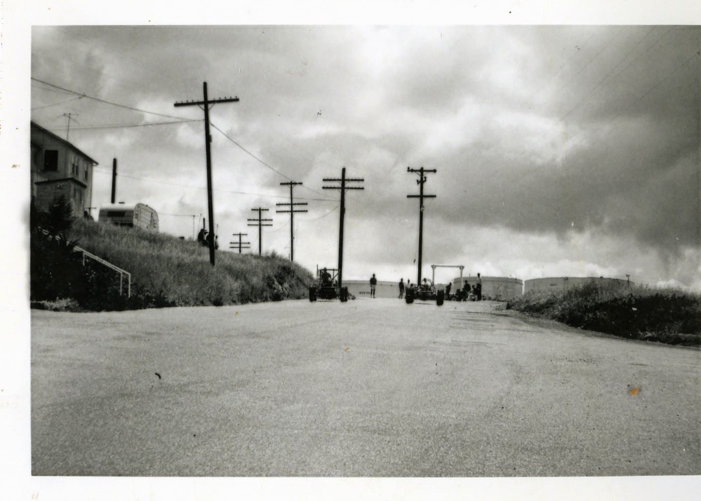 A black and white photo of power lines on the side of a road.