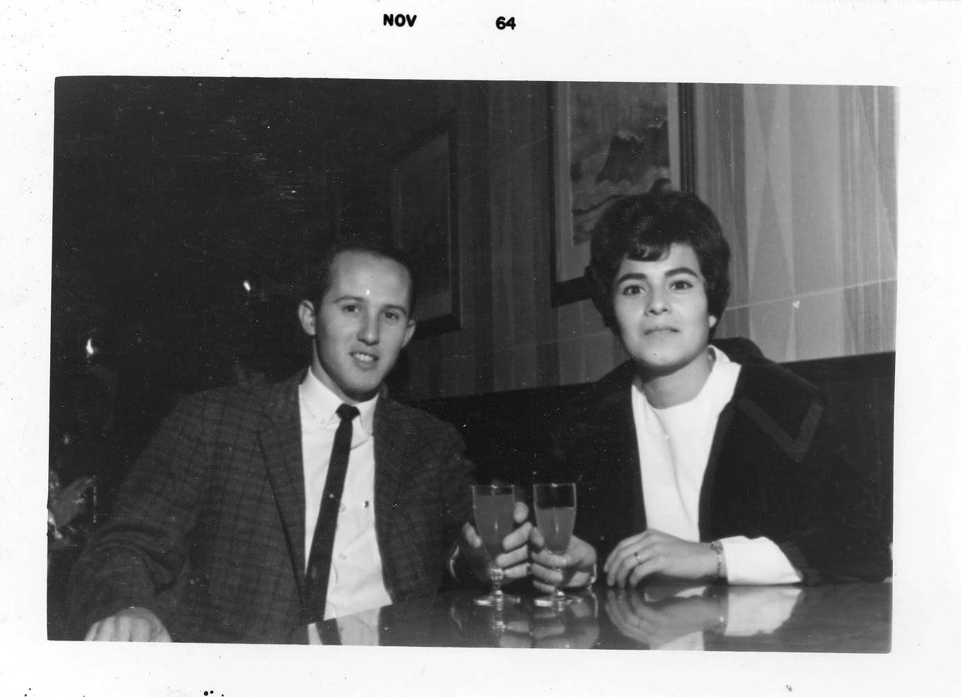A man and woman sitting at a table with drinks.