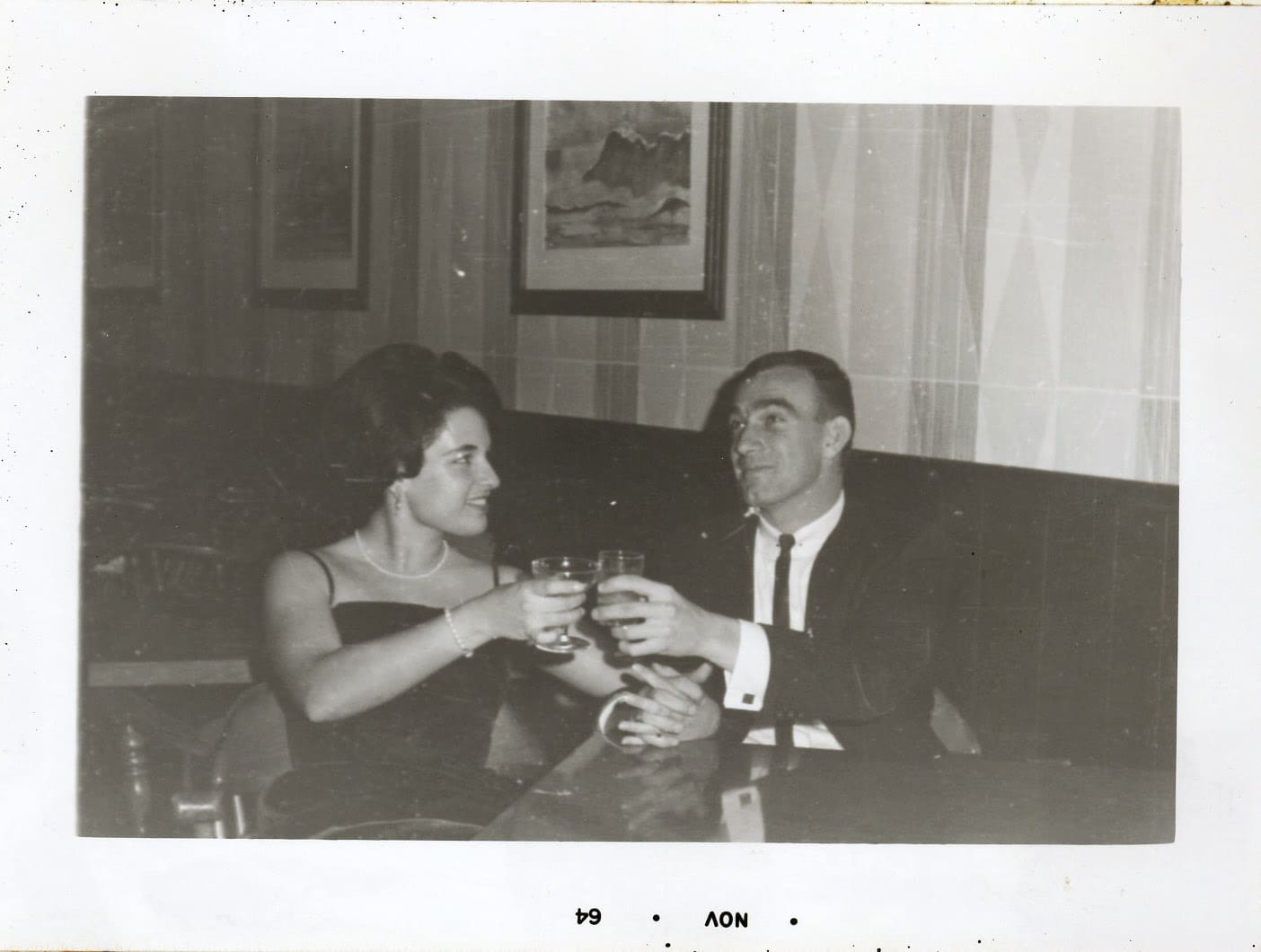 A man and woman sitting on the couch drinking wine.