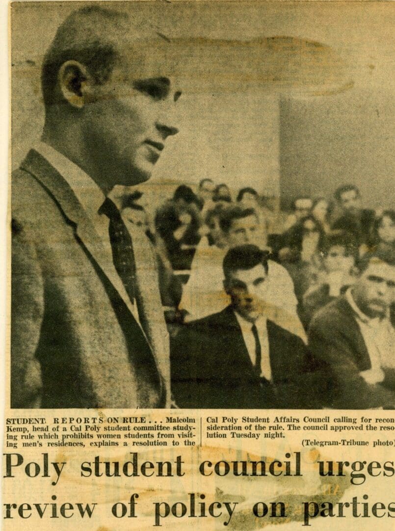 A man in suit and tie standing next to a crowd.