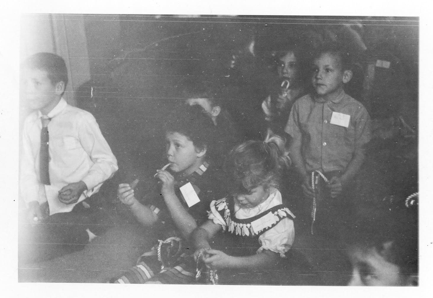 A group of children sitting together in front of a wall.