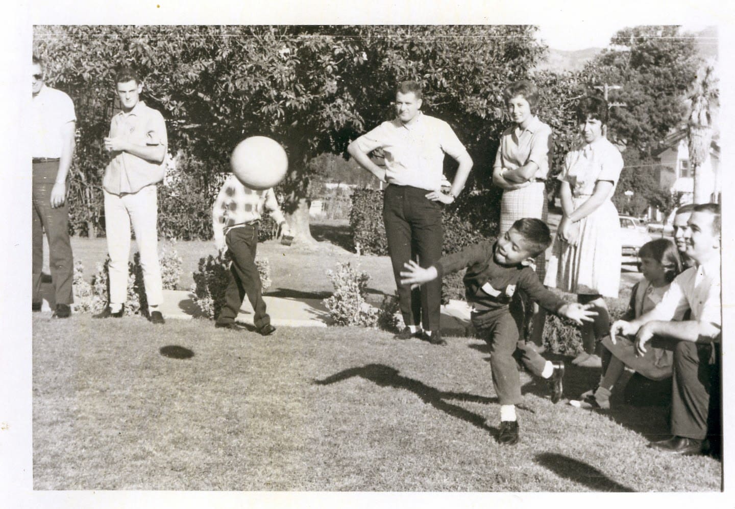 A group of people standing around in the grass.