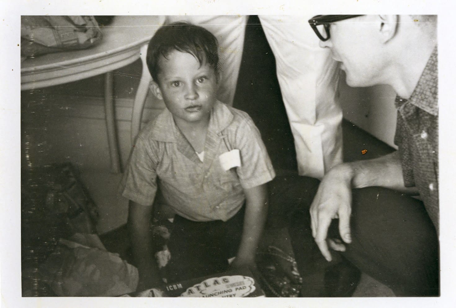 A young boy sitting on the floor with his head down.