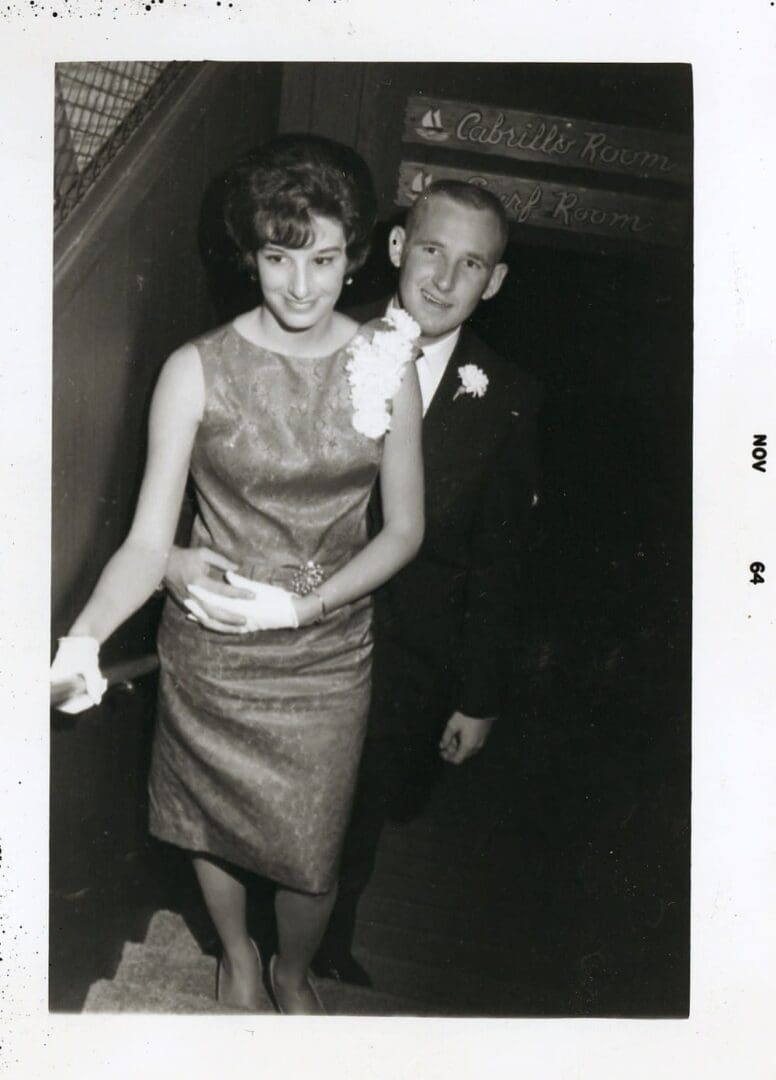 A man and woman in formal wear walking down stairs.