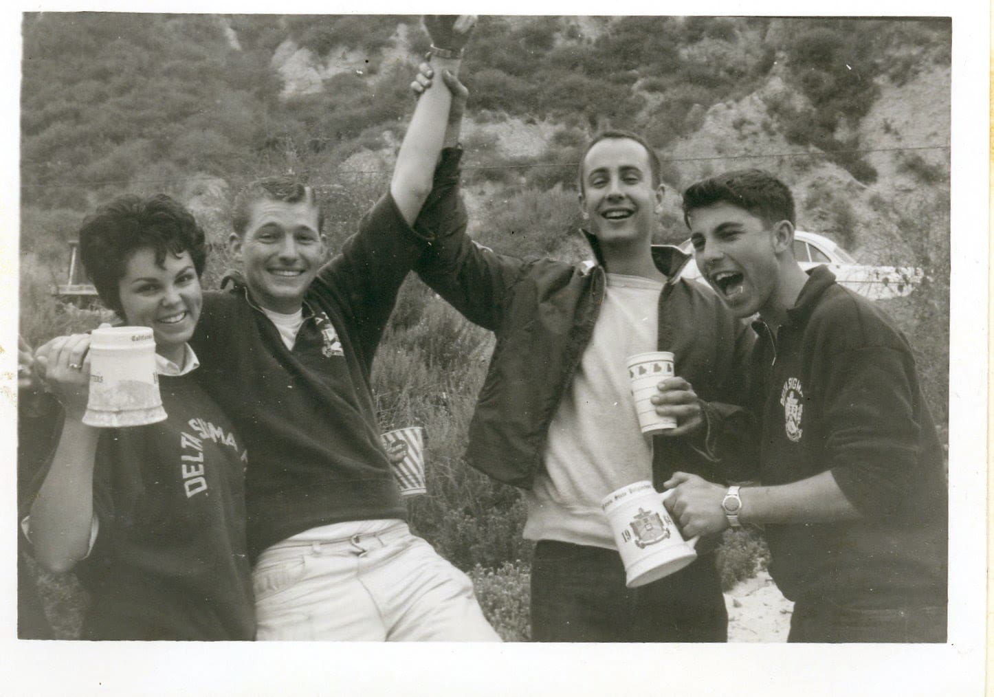 A group of people holding drinks and posing for the camera.
