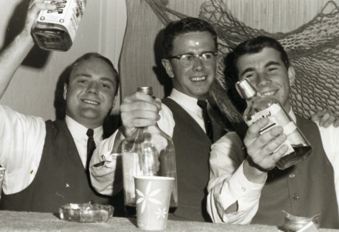 Three men sitting at a table with drinks and food.