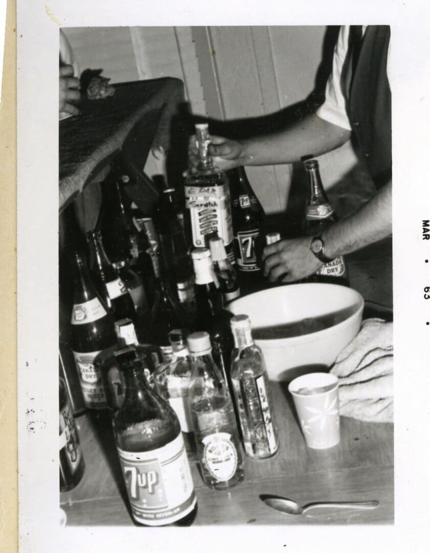 A man sitting on the floor with many beer bottles.