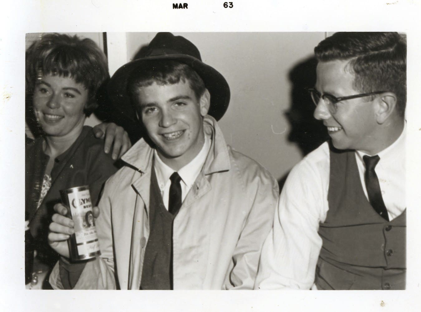 A man in a hat and tie with two other men.
