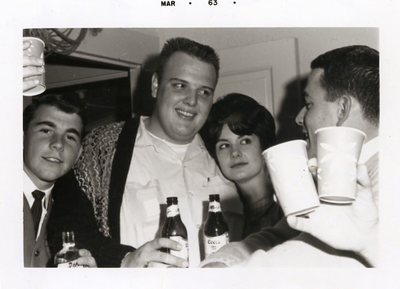 A man and two women are holding beers.