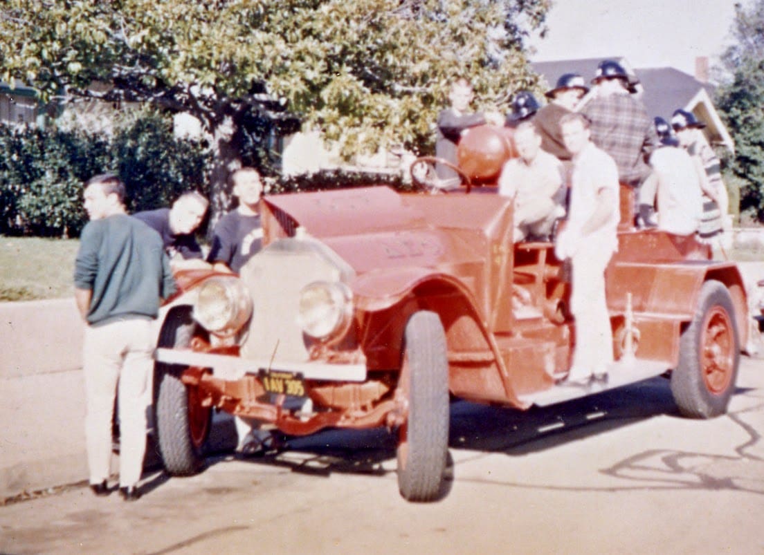 A group of people standing around an old fire truck.