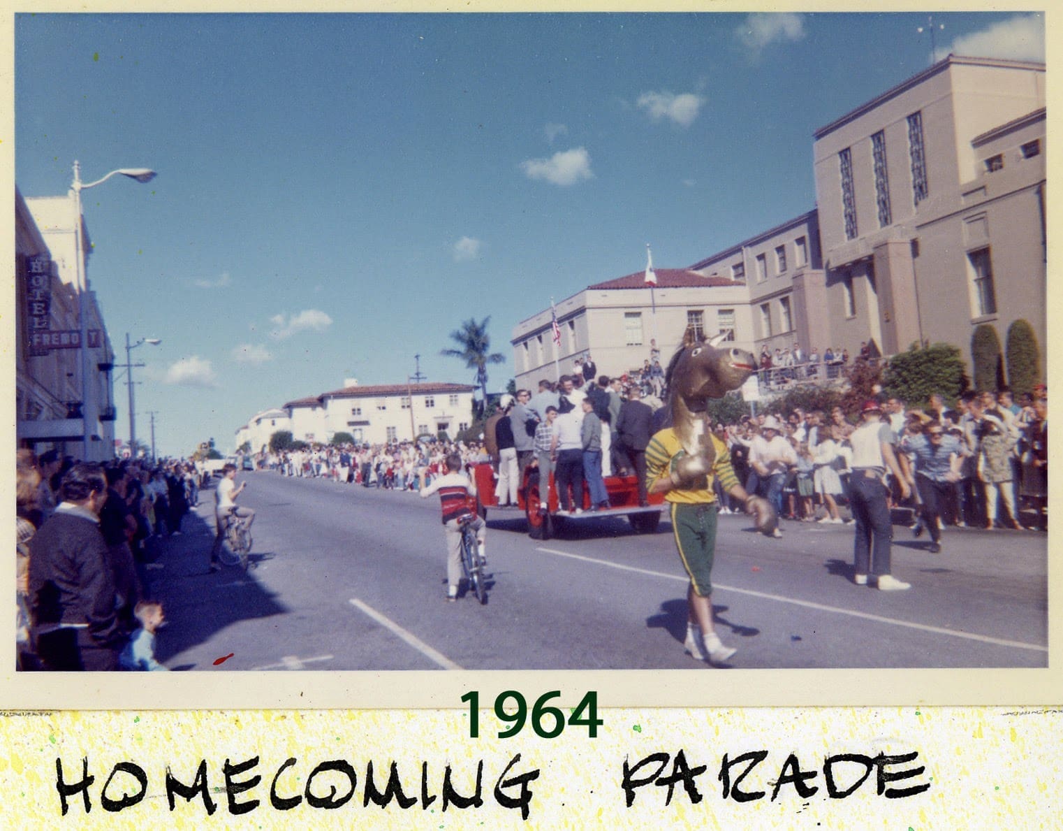 A parade is going down the street in front of some buildings.