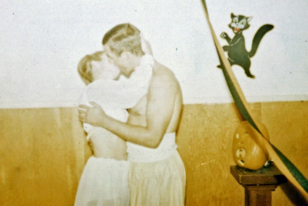 A man and woman kissing in front of a wall.