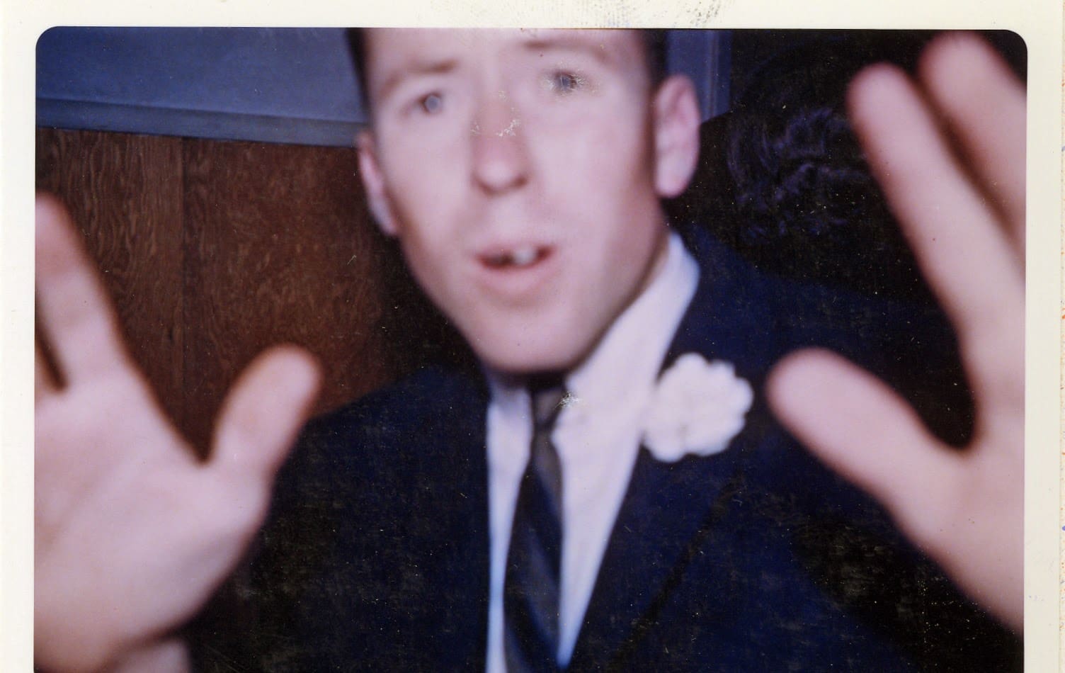 A man in a suit and tie with his hands up.