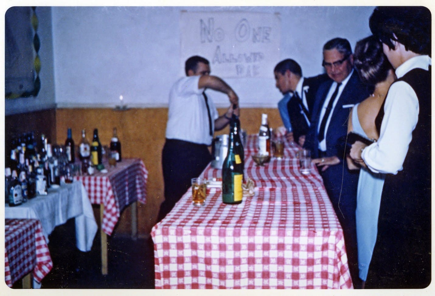 A group of men standing around a table with wine bottles.