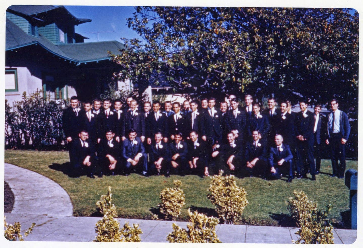 A group of men in suits and ties standing on top of grass.
