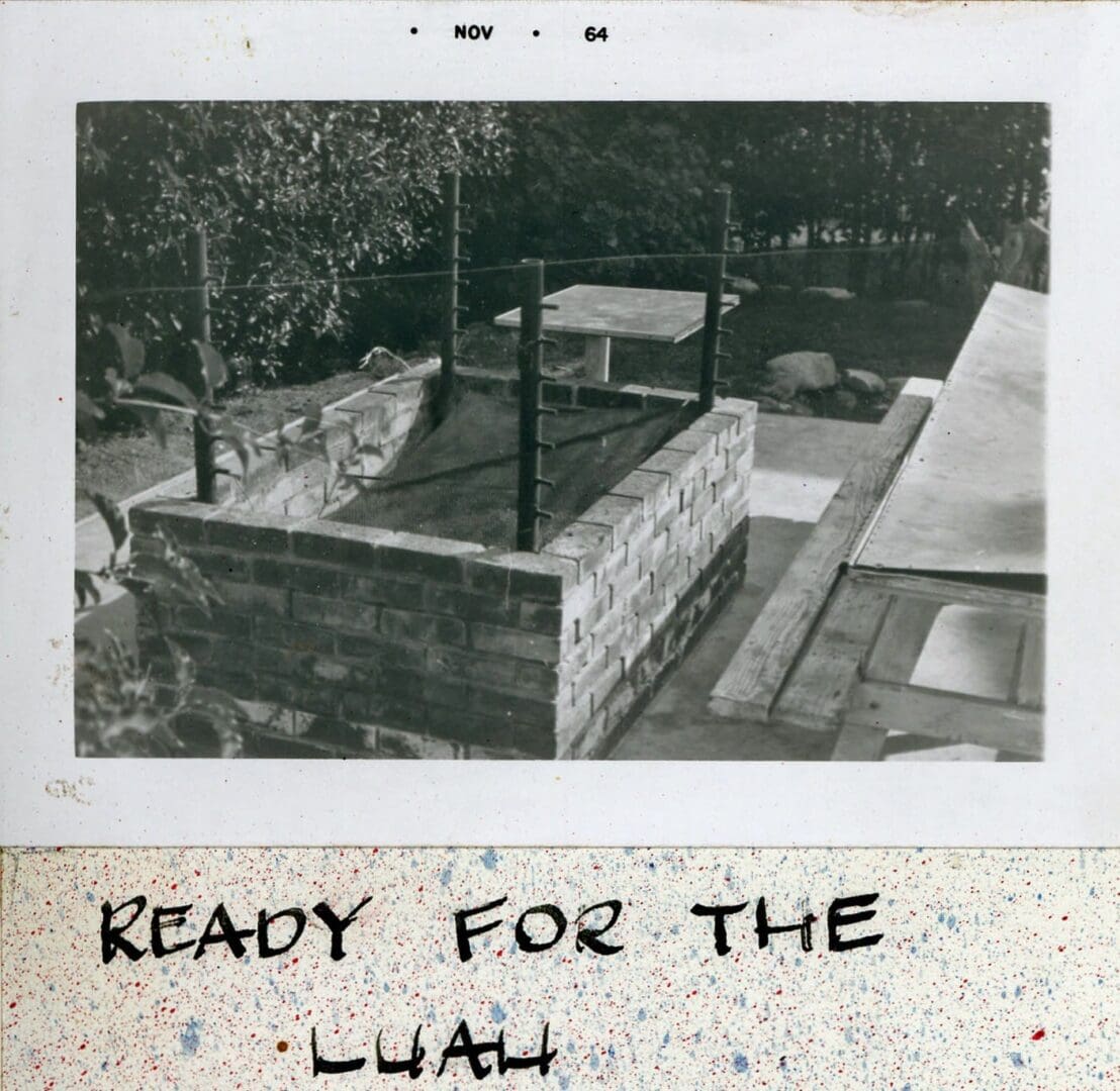 A polaroid of the back yard with a pool and a bench.