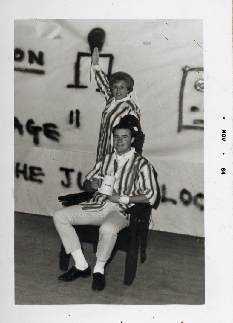 Two men sitting in a chair with graffiti on the wall.