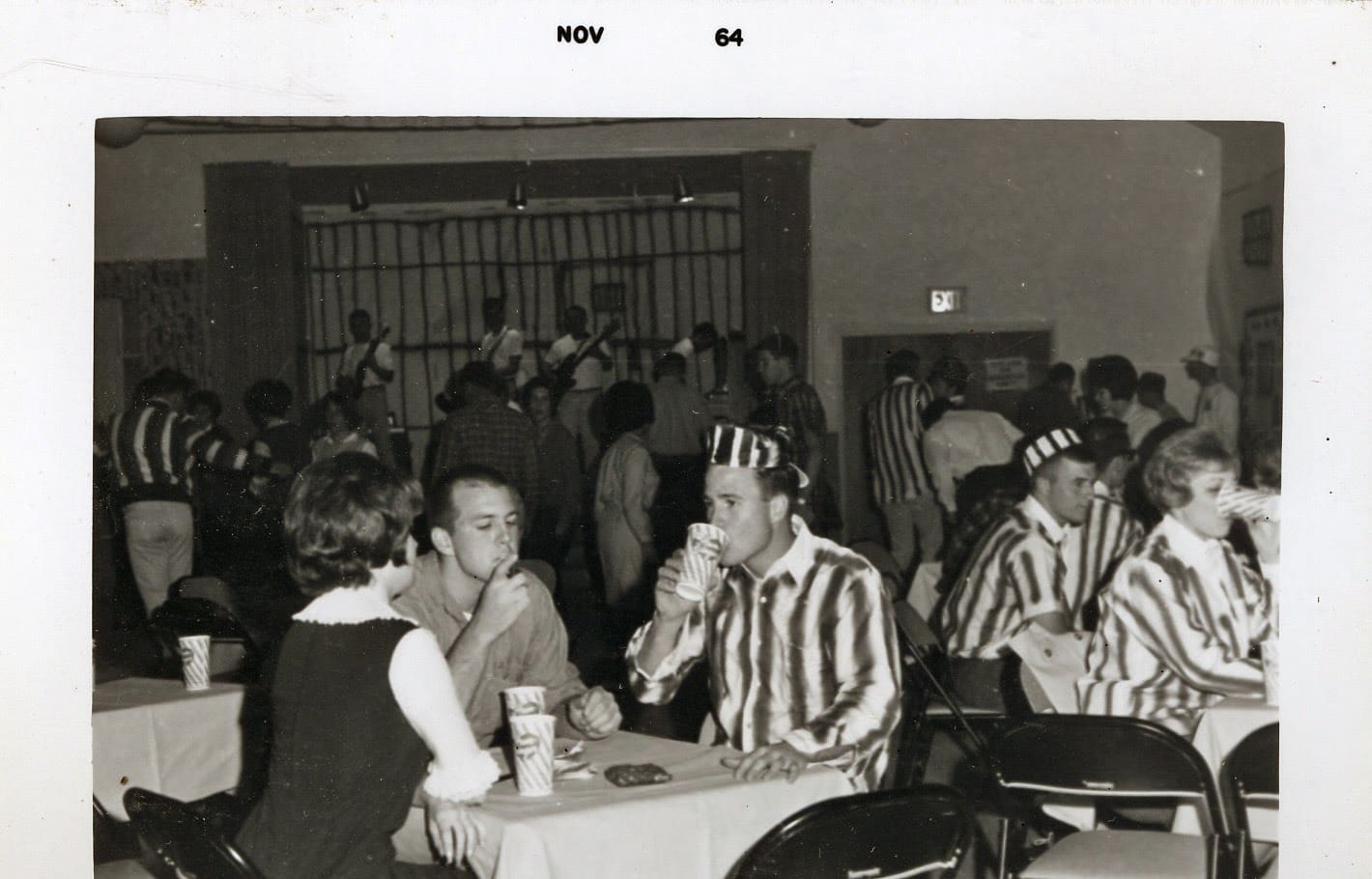A group of people sitting at tables in front of a wall.