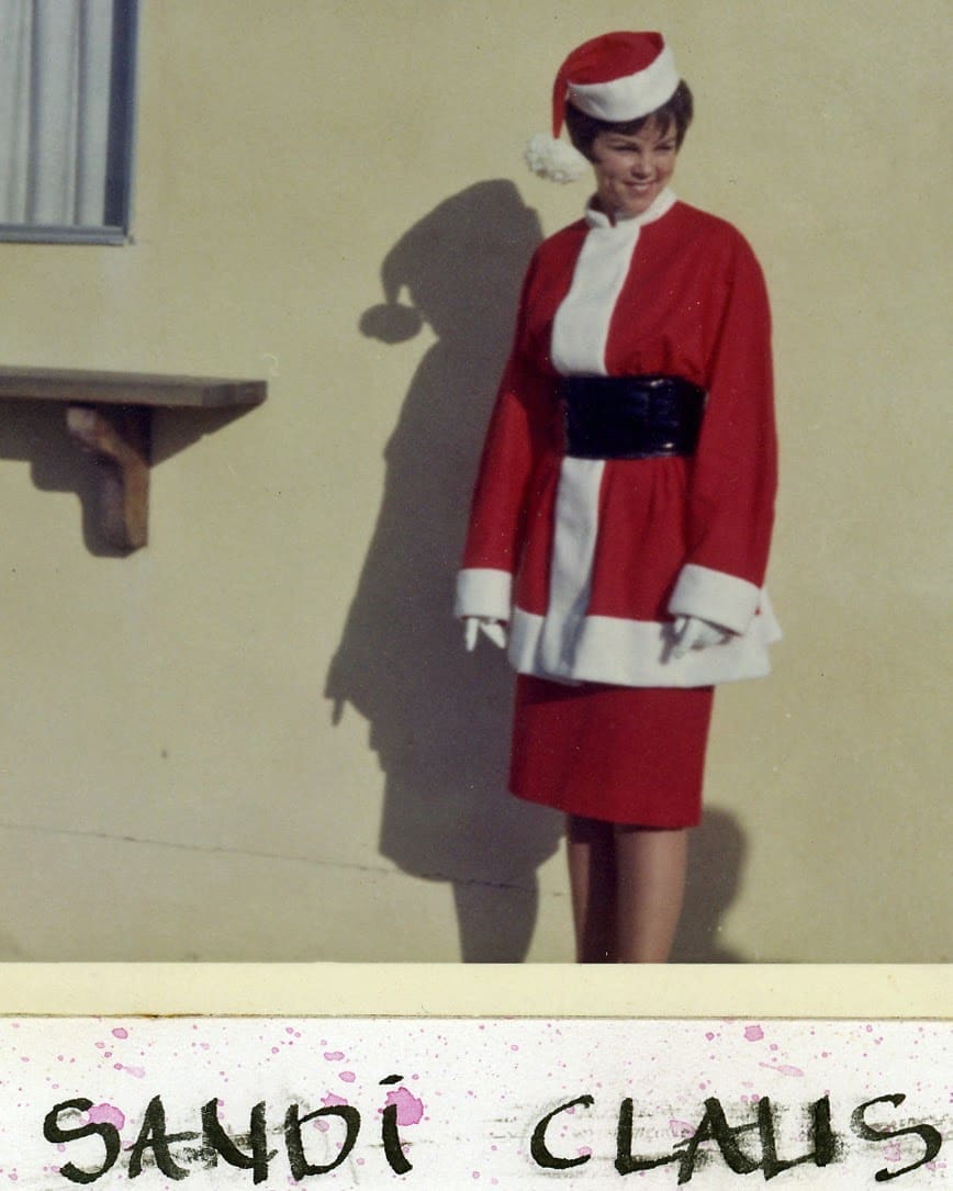A woman in a santa suit standing on the side of a building.