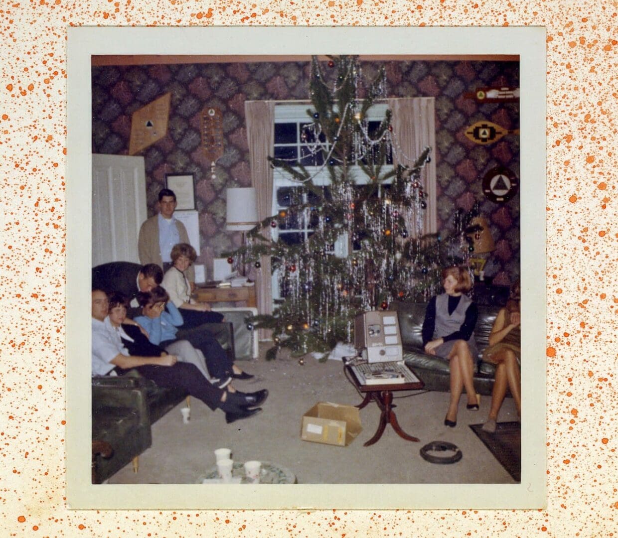 A group of people sitting around in front of a christmas tree.