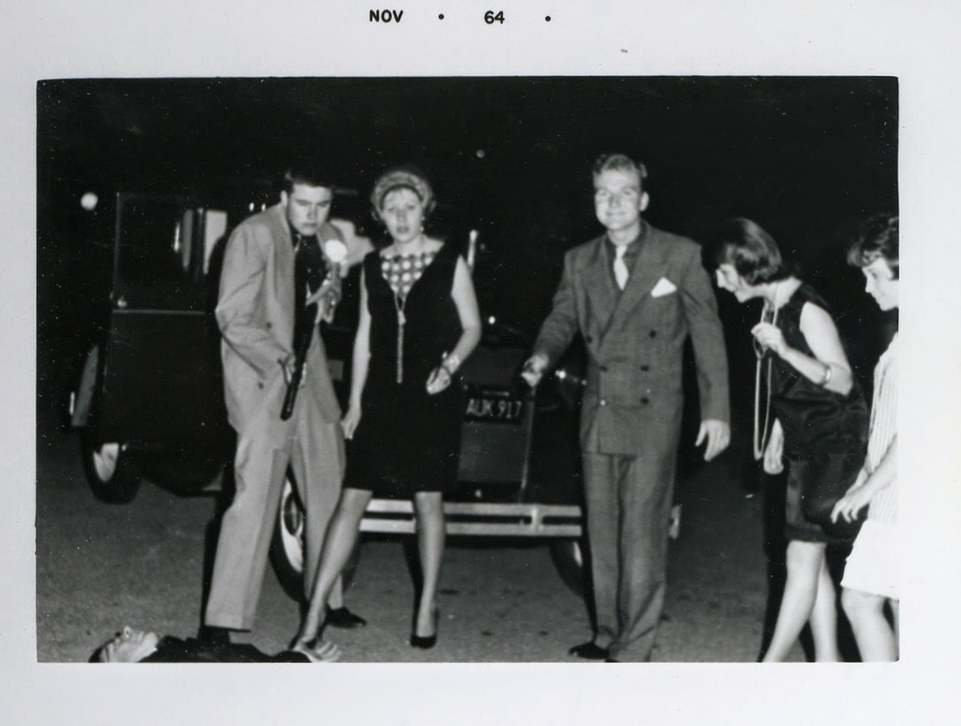 A group of people standing around a car.