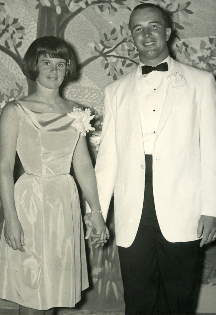 A man and woman holding hands in formal wear.