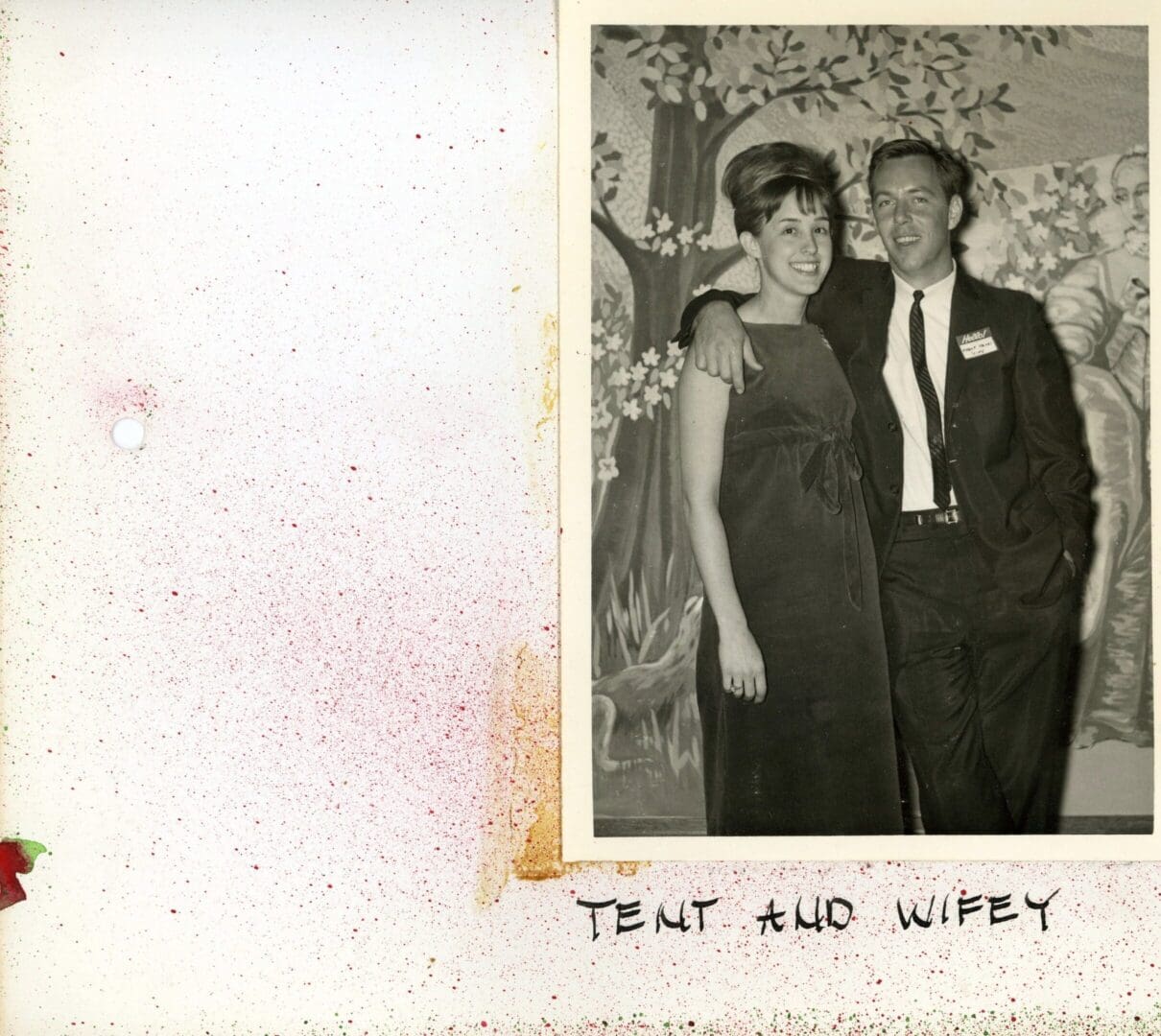 A couple posing for a picture in front of a floral arrangement.