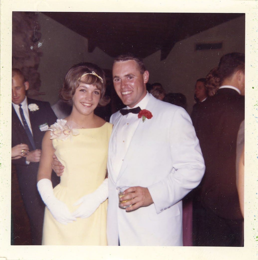 A man and woman pose for the camera at an event.