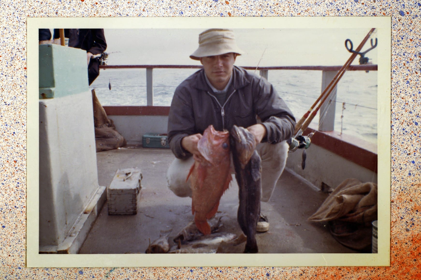 A man holding fish on the deck of his boat.